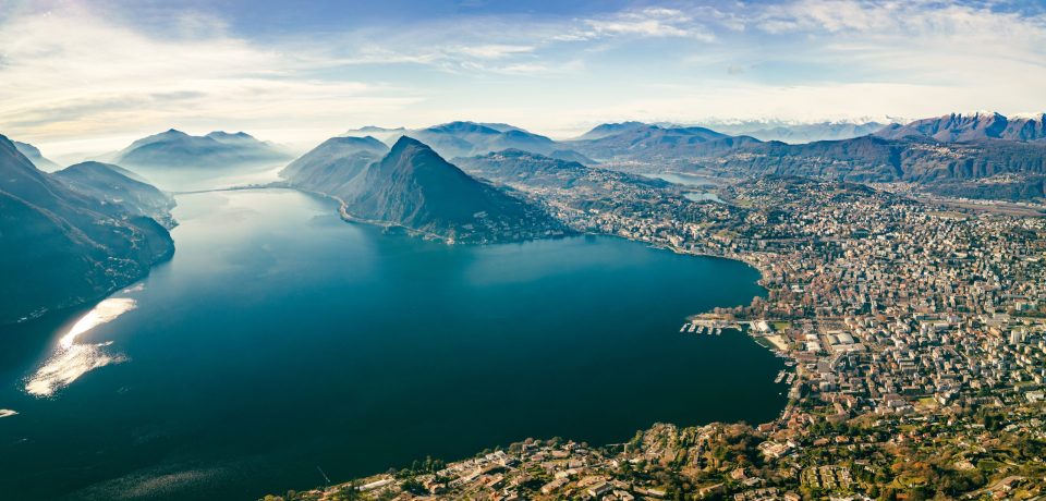 Lugano, Schweiz. Erstaunlicher Blick aus der Luft auf die Schweizer Stadt, umgeben von See und Bergen.